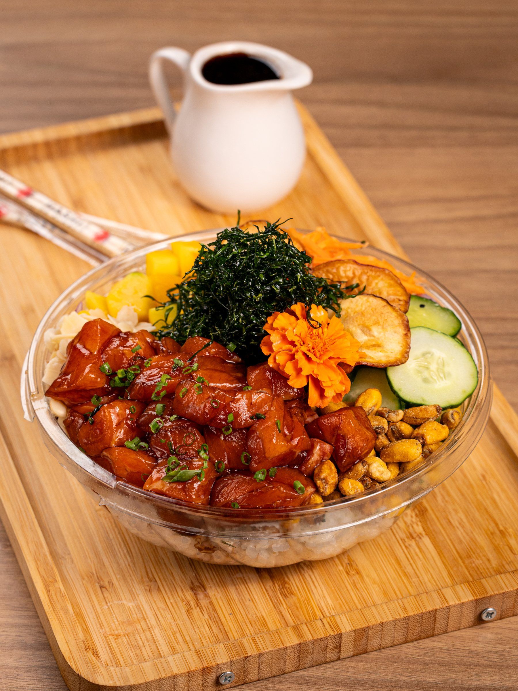 Poke de salmão marinado em shoyu com manga, nori, pepino e milho crocante, servido em bowl sobre tábua de bambu