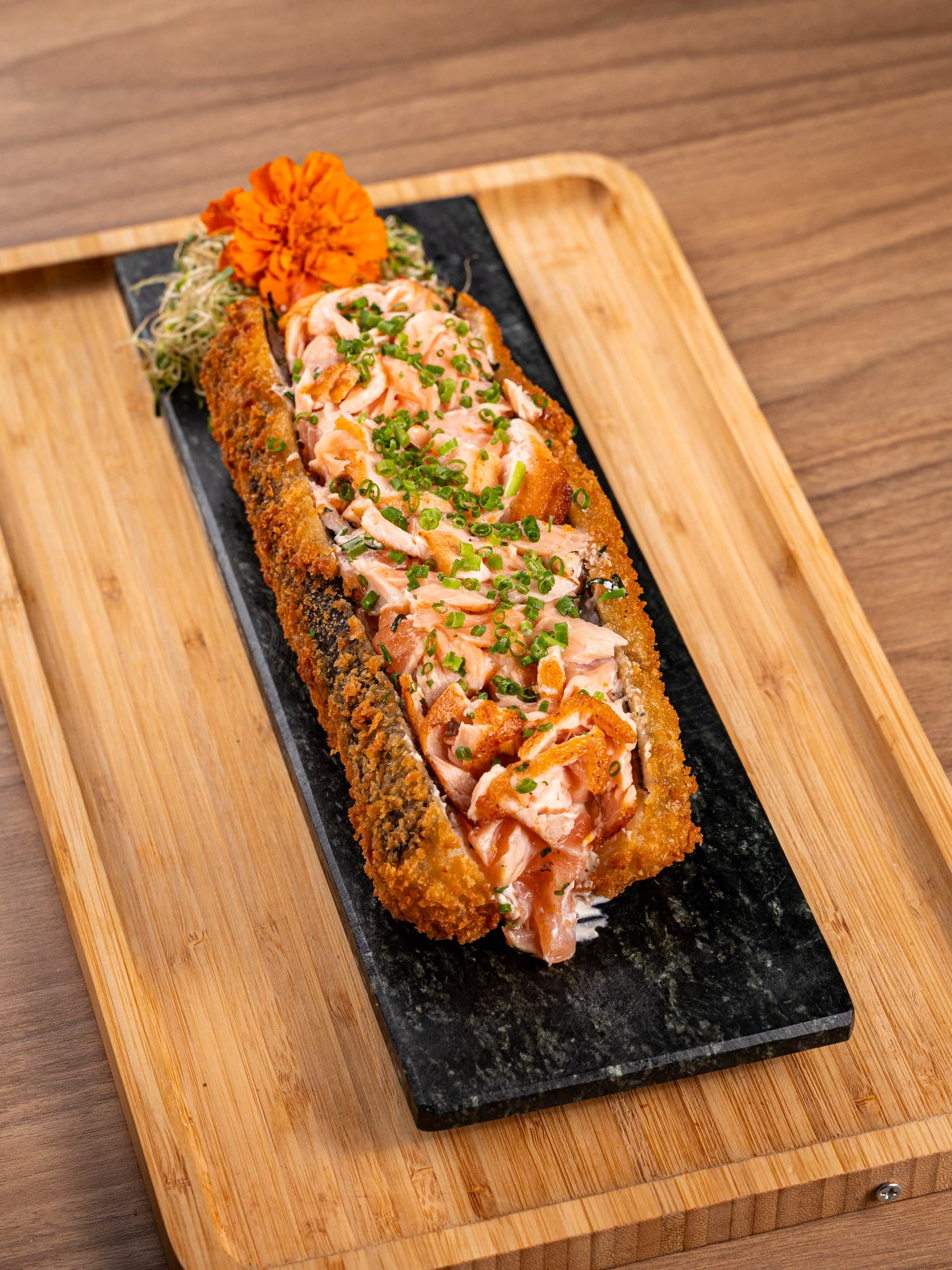 Big hot roll com salmao grelhado maçaricado e maionese, sobre ardosia e tabua de bambu