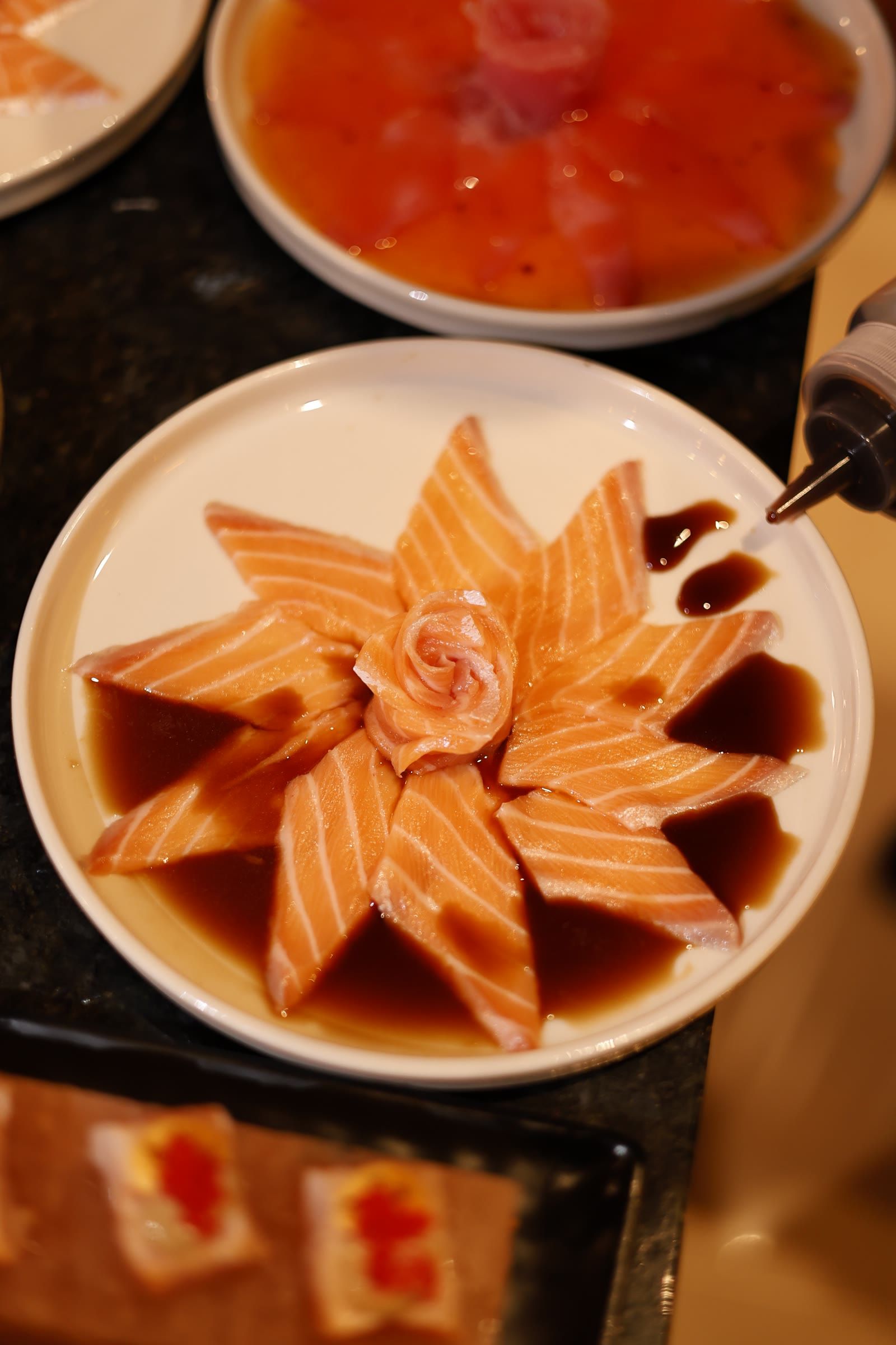 Bisnaga pinga shoyu no prato de salmão em flor, com bandeja de niguiris embaixo.